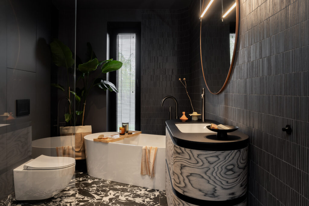 Dom w duchu wabi sabi – elegancka łazienka z wolnostojącą wanną, czarnymi płytkami i designerską umywalką