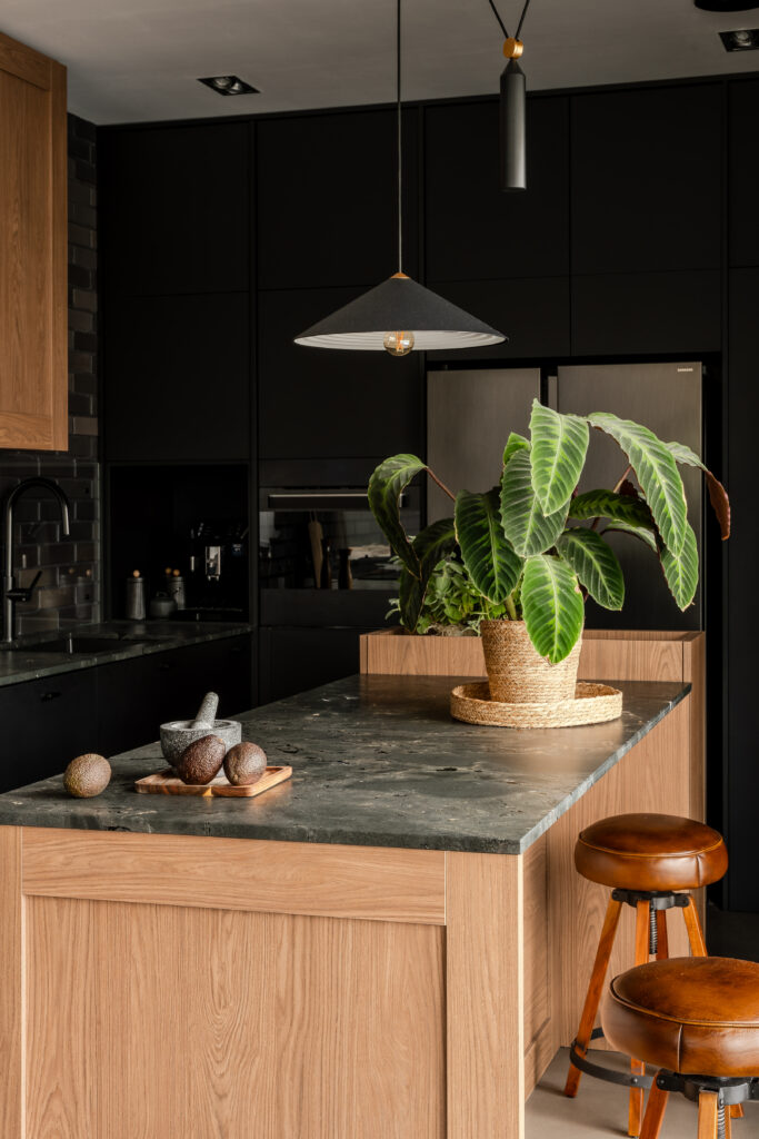 Industrialny dom – kuchnia w stylu industrialnym z połączeniem czerni, naturalnego drewna i ukrytą spiżarką.