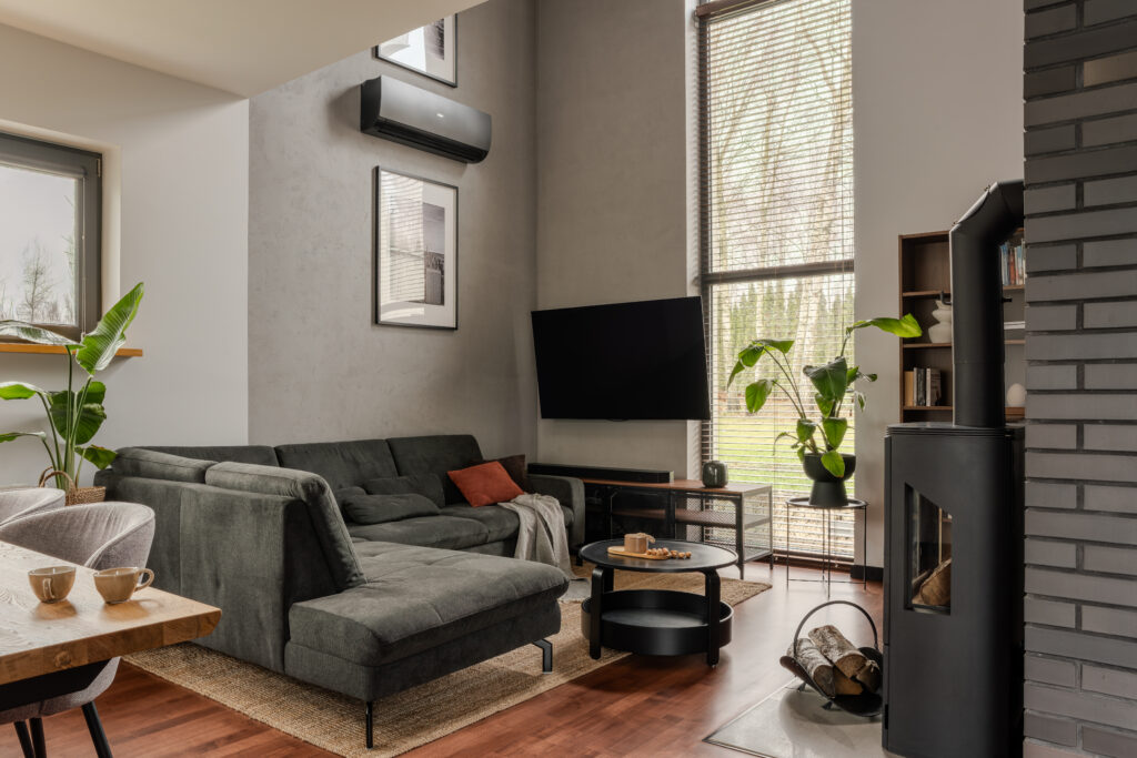 Industrialny dom – salon z betonową ścianą, grafitową cegłą i strefą wypoczynkową.