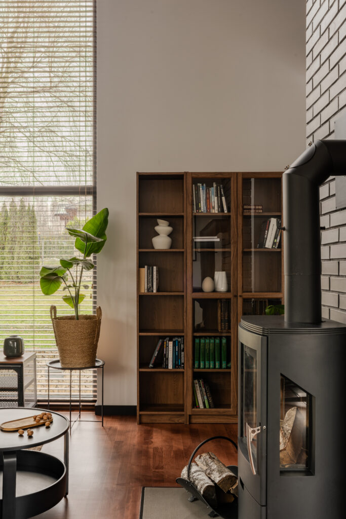 Industrialny dom – salon z kominkiem, czarnymi akcentami i naturalnym drewnem w wykończeniach.
